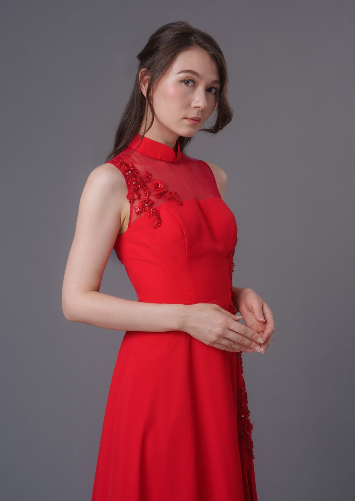 Qipology bridal - Sleeveless Wedding Qipao in classic red, featuring a mandarin collar in A-line silhouette; perfect for tea ceremony and evening banquet. (half body side view front picture)